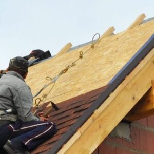 Roofing Construction and Building New Brick House with Modular Chimney, Skylights, Attic, Dormers and Eaves Exterior. Roofers Install, Repair Asphalt Shingles or Bitumen Tiles on the Rooftop Outdoor.
