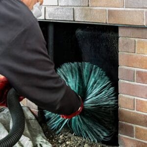 Chimney sweep wearing a mask for protection whilst cleaning chimney - screwing the chimney sweep brush as it ascends the chimney