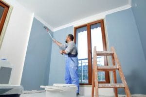 man painting blue on wall