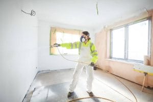 man painting white paint on wall